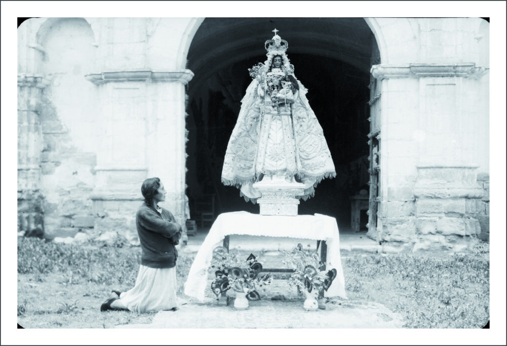 Mujer rezando ante la imagen de la Virgen María. S/f.